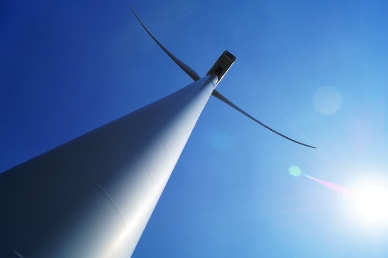 low angle shot of a wind turbine against a blue sky
