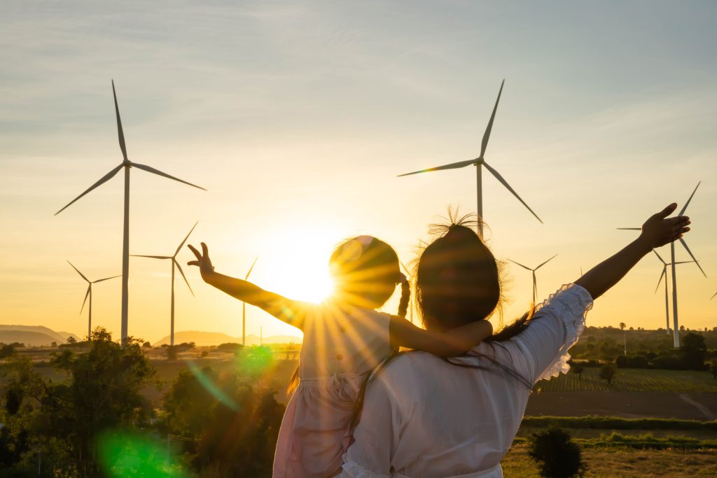 mother and daughter with wind turbines in the background