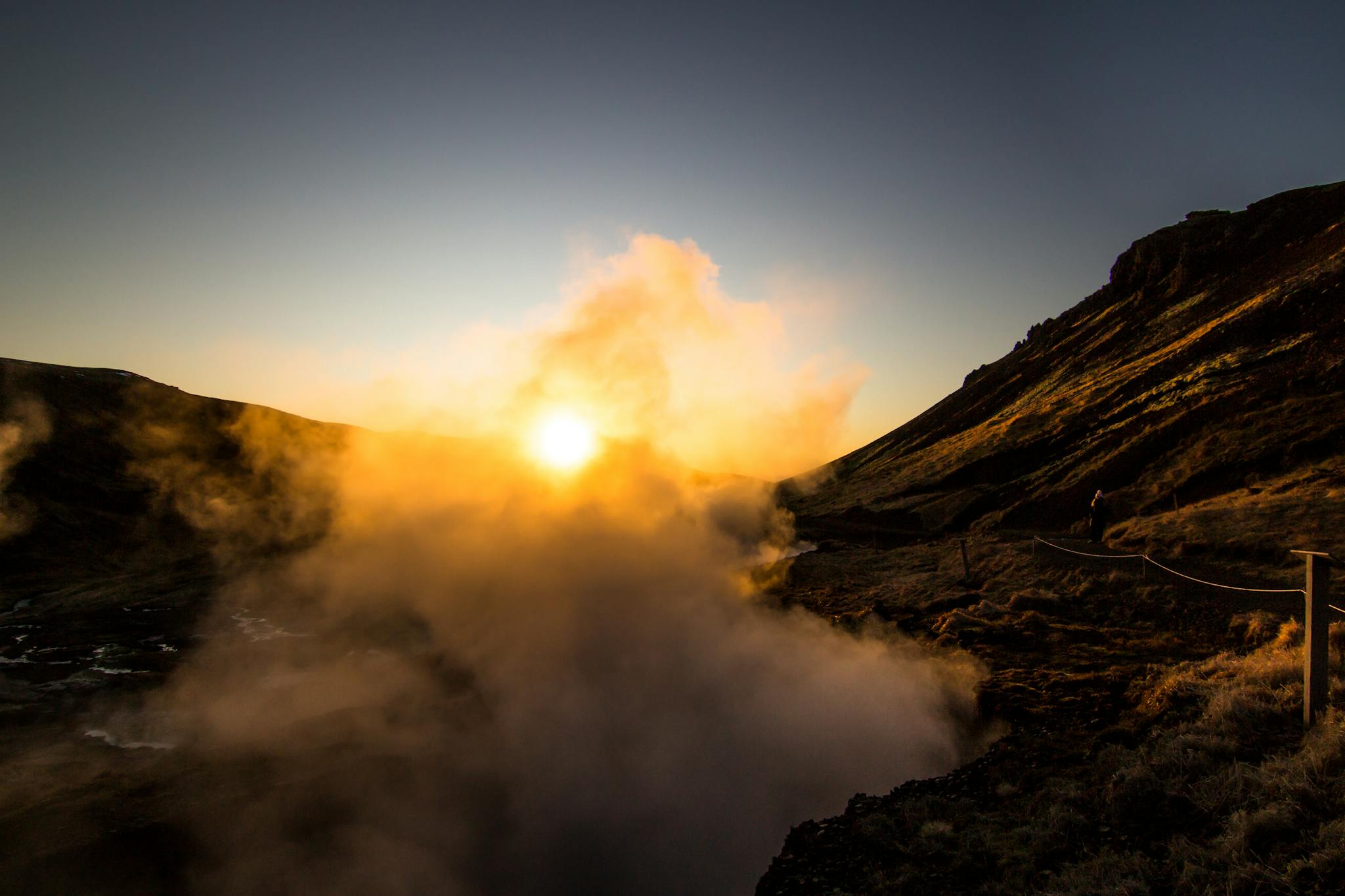 Stunning Icelandic landscape at sunrise with dramatic fog and golden hues over the mountains.